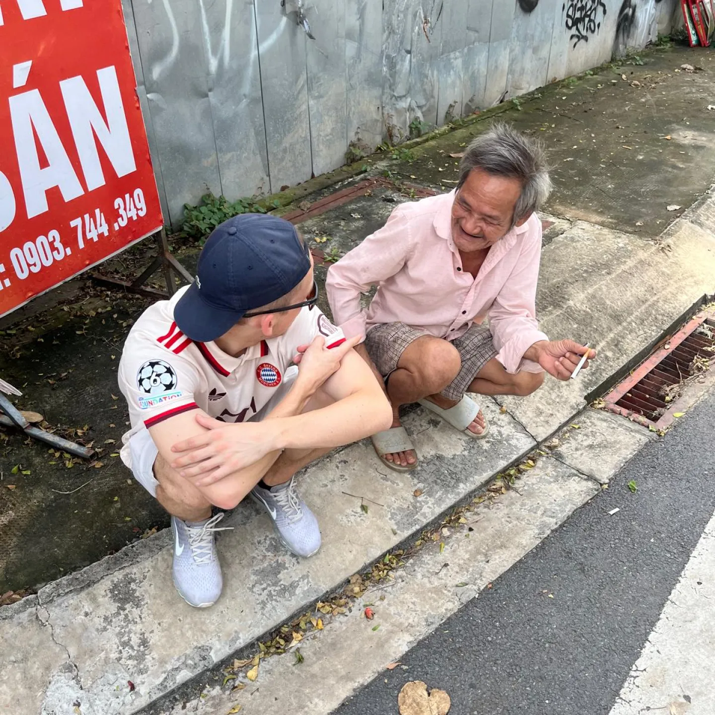 Der Autor zusammen mit einem Vietnamesen am Strassenrand sitzend