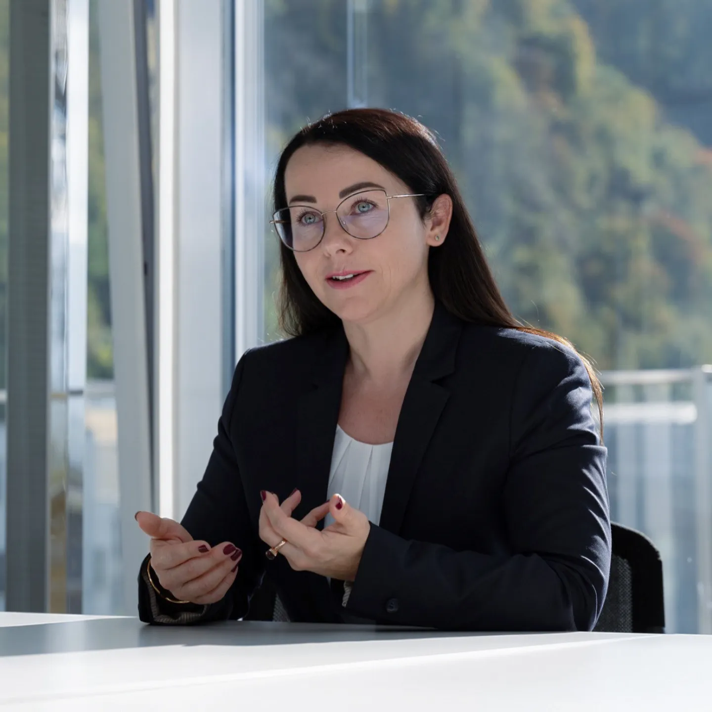 Businessporträt einer Referentin im Gespräch vor Fensterkulisse mit moderner Arbeitsumgebung