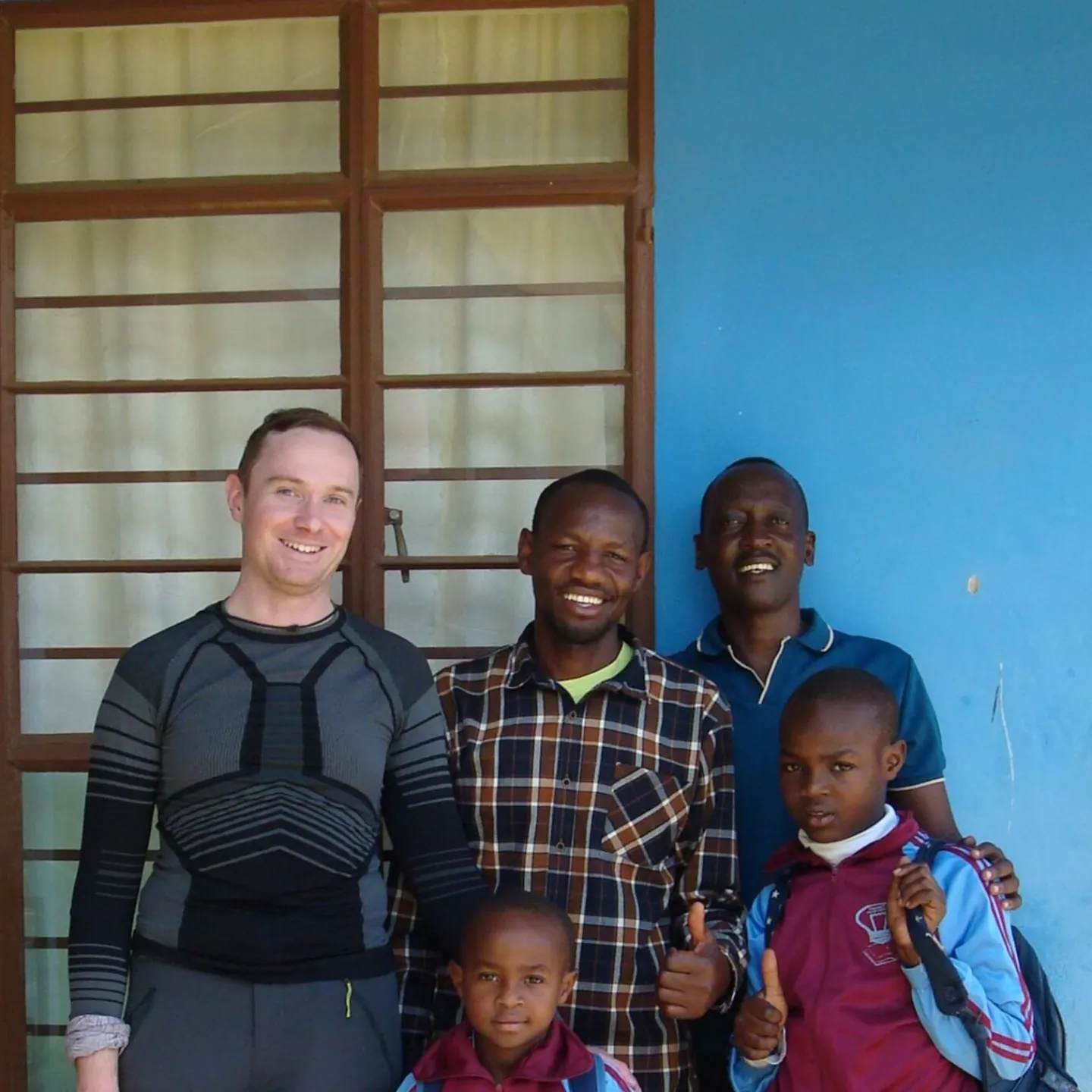 Gruppe von Personen steht vor einem blauen Gebäude.