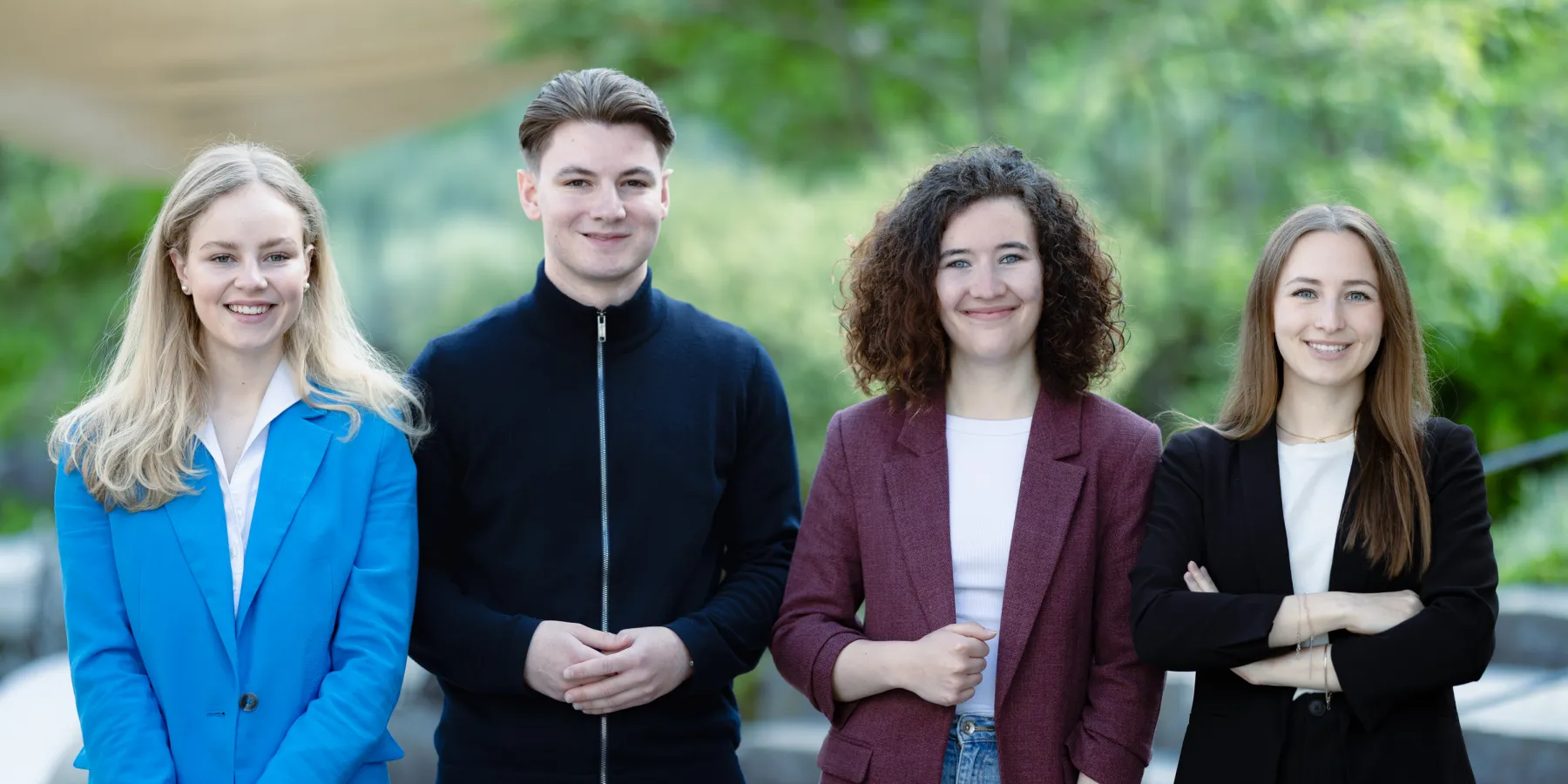 Vier Studierende der Universität Liechtenstein Bachelor BWL posieren gemeinsam im modernen Campusgebäude – Fokus auf studentische Vielfalt und Gemeinschaft.