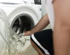 Student nutzt Waschmaschine im Studierendenwohnheim der Universität Liechtenstein.