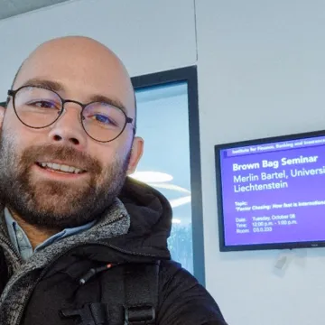 Mitarbeiter der Universität Liechtenstein vor Ankündigung eines Seminars zum Thema internationale Kapitalflüsse an der Wirtschaftsuniversität Wien.