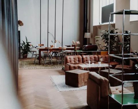 Gemütlicher Raum mit Sofas, Pflanzen und einem großen Tisch, ideal für Treffen und Networking-Veranstaltungen.