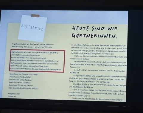 Ein Bildschirm zeigt eine Präsentationsfolie mit dem Titel "Heute sind wir Gärtnerinnen". Links oben ist ein Notizzettel mit der Aufschrift "Auf’strich" zu sehen. Der Text auf der Folie beschreibt kreative Ansätze in der Architektur und die Verbindung zur Natur.
