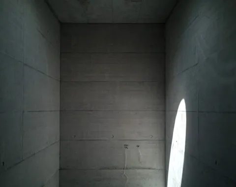 Minimalistischer Betonraum mit Oberlicht und Lichteinfall, der die schlichte Architektur betont.
