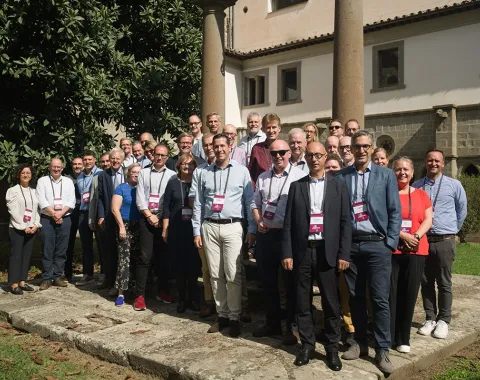 Gruppe von Menschen steht draußen vor einem historischen Gebäude während des ERCIS-Workshops in Viterbo, Italien. Sie tragen Namensschilder und lächeln in die Kamera.