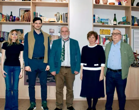 Gruppe von fünf Personen stehen vor einem Bücherregal.