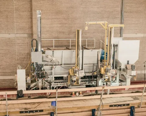 Produktionshalle für Lehmbau mit Maschinen und Holzstrukturen, die den Bauprozess veranschaulichen.