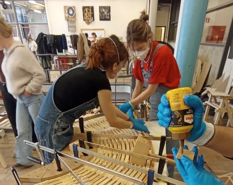 Ein Holzmodell eines Möbelstücks wird von Studierenden zusammengebaut.