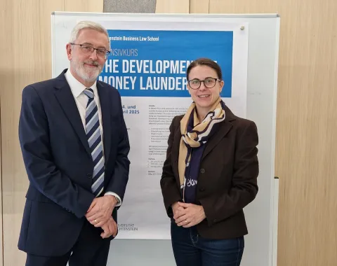 Zwei Personen stehen vor einem Poster des Intensivkurses „The Development of Money Laundering“ an der Universität Liechtenstein.