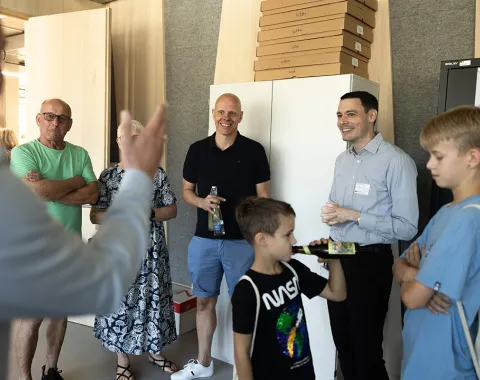 Gruppe von Menschen bei einer Führung im neuen Standort der Universität Liechtenstein, Ebaholz, während des Tags der offenen Tür. Ein Mann spricht zu den Besuchern, die aufmerksam zuhören.