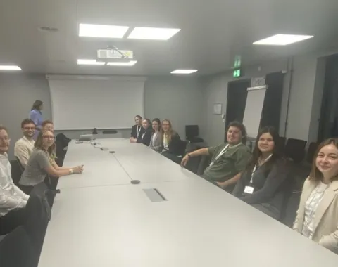 Studierende der Universität Liechtenstein sitzen in einem Konferenzraum bei Ivoclar in Schaan. Im Hintergrund ist eine Präsentationsleinwand zu sehen.