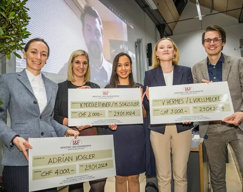 Fünf Studierende der Universität Liechtenstein halten große Schecks als Gewinner des I&F Family Wealth Preservation Awards. Im Hintergrund ist eine Person auf einem Bildschirm zu sehen.