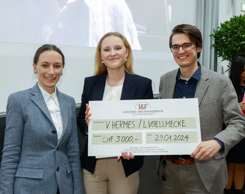 Drei Personen halten einen großen Scheck mit der Aufschrift "I&F Family Wealth Preservation Award" in einem Veranstaltungsraum. Sie lächeln in die Kamera.