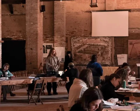 Bild in Brauntönen mit jungen Menschen an Zeichentischen