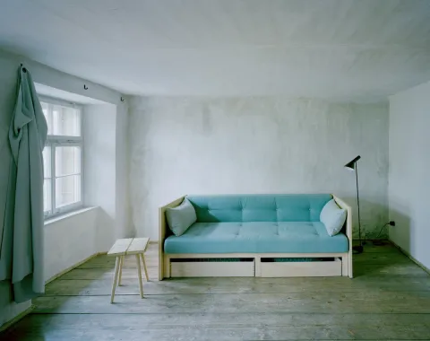 Minimalistischer Wohnraum mit Sofa und Fensterlicht in ruhiger Innenarchitektur