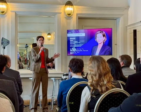 Referentin spricht vor Publikum bei Netzwerkveranstaltung mit Bildschirmpräsentation im Hintergrund