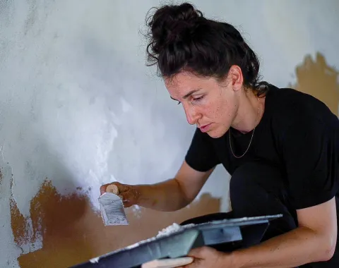 Person streicht Innenwand bei Renovationsarbeiten in historischem Gebäude, Detailaufnahme Handwerk und Architektur