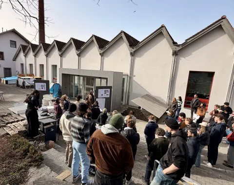 Mehrere junge Menschen neben einem Gebäude mit Shed-Dach