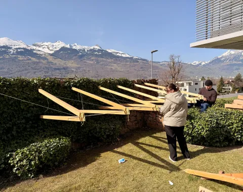 Drei junge Menschen bauen eine Konstruktion aus Holz 