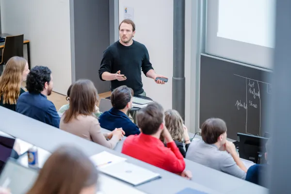 Ein Dozent hält eine Präsentation im Hörsaal der Universität Liechtenstein vor einer Gruppe Studierender.