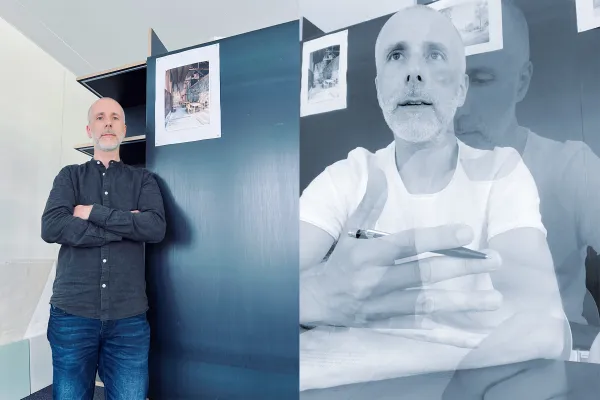 Architekturdozent steht vor einem schwarzen Präsentationsmodul und spricht mit Studierenden über Entwurfsskizzen an der Universität Liechtenstein