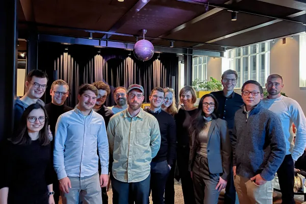 Alumni Gruppe posiert gemeinsam für ein Gruppenfoto bei einer Abendveranstaltung mit stimmungsvoller Beleuchtung.