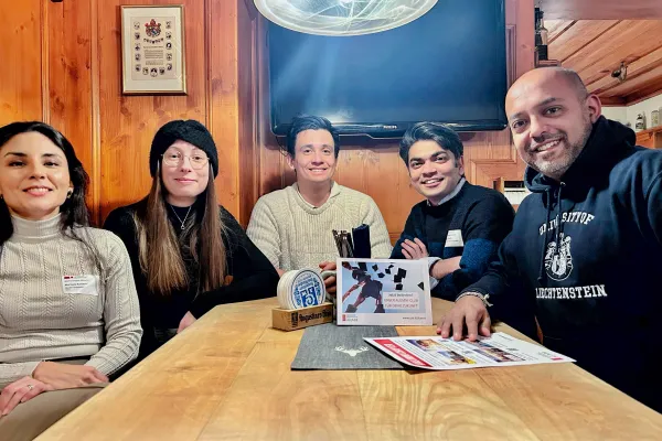 Sechs Alumni der Universität Liechtenstein sitzen an einem Holztisch und sprechen über den Alumni Club.