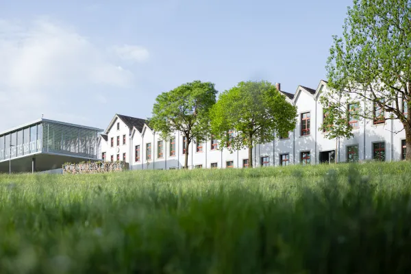 Universitaet Liechtenstein Gebaeude mit weissem Mauerwerk und gruener Wiese im Vordergrund.