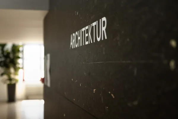 Beschriftung „Architektur“ auf dunkler Wand im Gebäude der Universität Liechtenstein.
