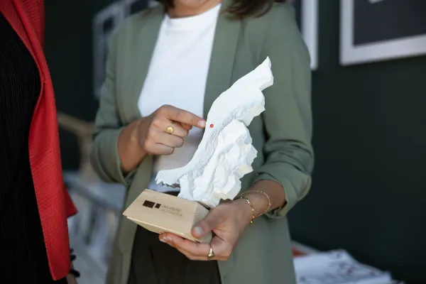 Nahaufnahme eines 3D-Modells von Liechtenstein mit markiertem Punkt, gehalten von einer Frau in Businesskleidung.