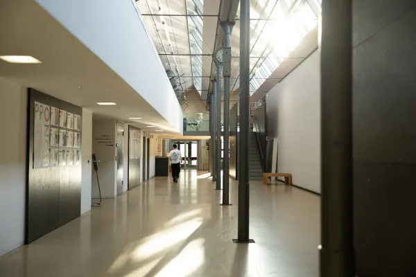 Heller Flur mit Uhr, Sitzgelegenheiten und Zugang zu Hörsälen an der Universität Liechtenstein.