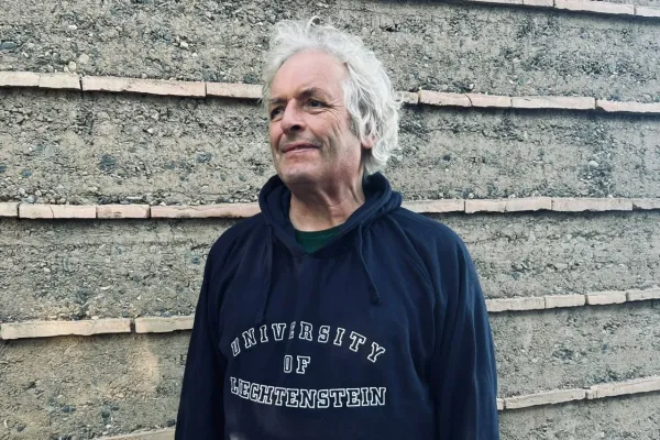 Martin Rauch mit einem Pullover der Universität Liechtenstein vor einer Lehmwand