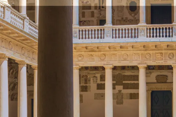 Historischer Innenhof der Universität Padua mit Säulen und verzierten Fassaden, beleuchtet von Sonnenlicht.