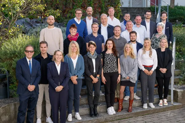 Gruppenfoto von Studierenden und Dozenten des Executive Master of Laws (LL.M.) im Gesellschafts-, Stiftungs- und Trustrecht an der Universität Liechtenstein. Die Gruppe steht auf einer Treppe im Freien, umgeben von grüner Vegetation.