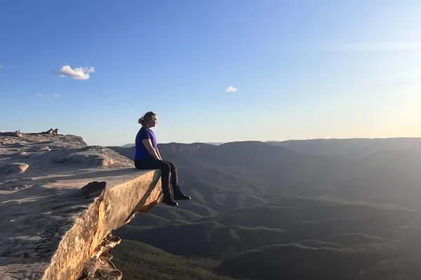 Eine Studierende der Universität Liechtenstein sitzt während ihres Auslandsaufenthalts auf einem Fels über einer Schlucht