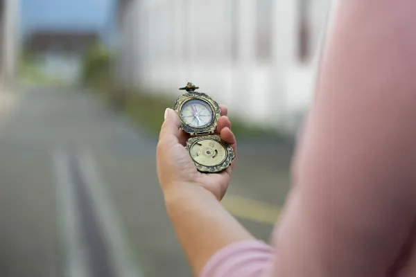 Hand hält antiken Kompass im Außenbereich der Universität Liechtenstein.