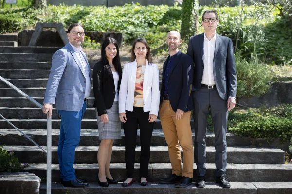 Dozierende und Mitarbeitende der Business School der Universität Liechtenstein posieren gemeinsam für ein Gruppenfoto im Freien.