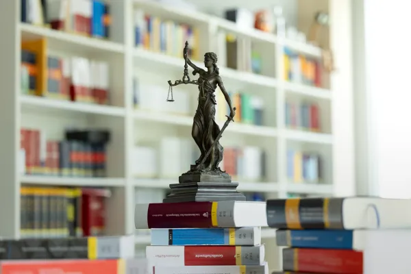 Justitia-Statue auf einem Stapel juristischer Bücher in der Bibliothek der Universität Liechtenstein.