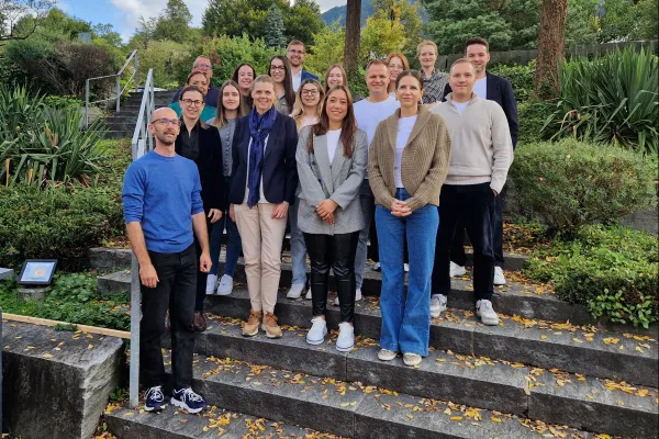 Gruppe von Erwachsenen steht auf Treppe in grüner Umgebung.