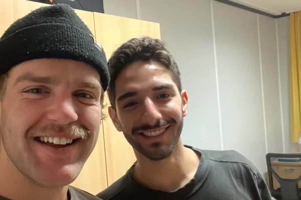 Zwei Studierende halten lächelnd Getränkedosen in die Kamera.