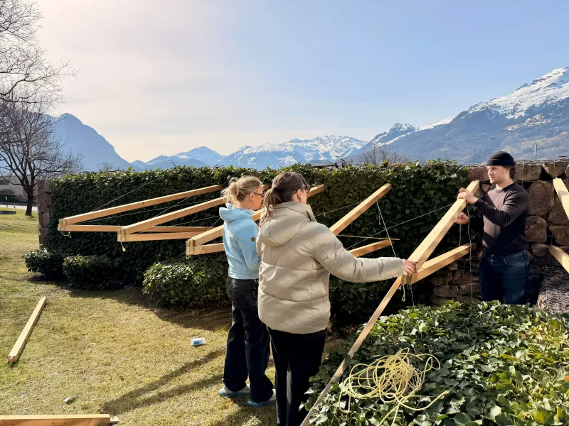 Drei junge Menschen bauen eine Konstruktion aus Holz 