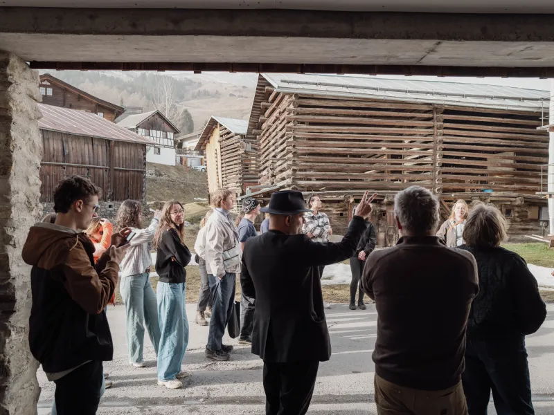 Gruppe von Menschen in einem Dorf mit Holzhäusern