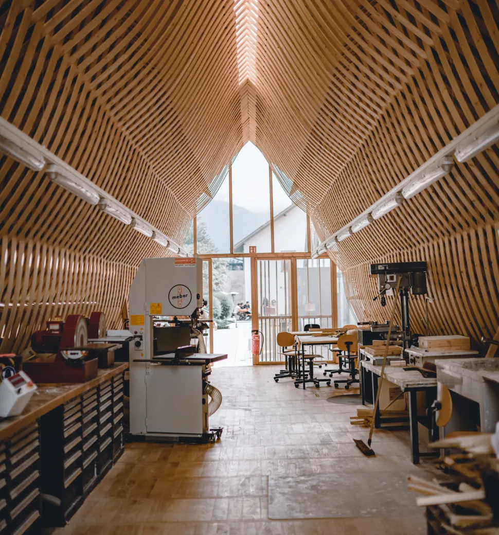 Gesamtsicht der hellen Holzwerkstatt mit Maschinen, Werkbänken und Fenstern